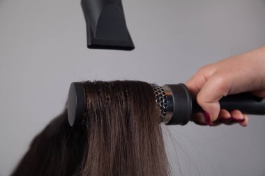 Profesyonel kuaför kadın, beyaz kadının saçını kurutuyor..