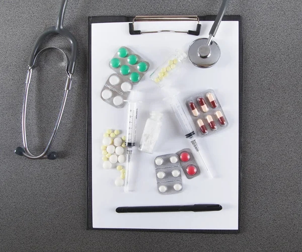 医生服务台 听诊器 笔记本和药丸 灰色背景 医学的概念 — 图库照片