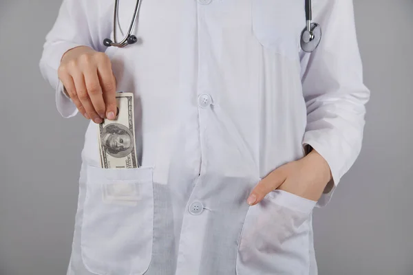 Kadın doktor bir dolar tutuyor. Yozlaşma ya da rüşvet konsepti. Doktor rüşveti cebine koyuyor..