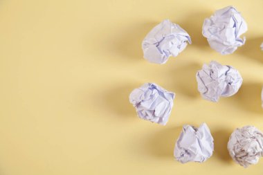 İzole edilmiş sarı arka planda buruşmuş kağıt toplar..