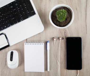 Ahşap arka planda akıllı telefon, kulaklık, dizüstü bilgisayar ve aksesuarlar.