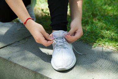  Koşucu kadın spor ayakkabılarını bağlıyor. Açık havada.. 