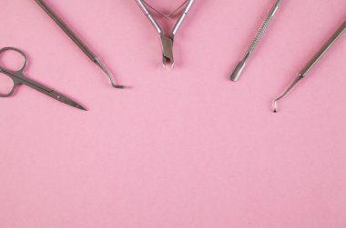 İzole edilmiş pembe arka planda manikür aksesuarları.