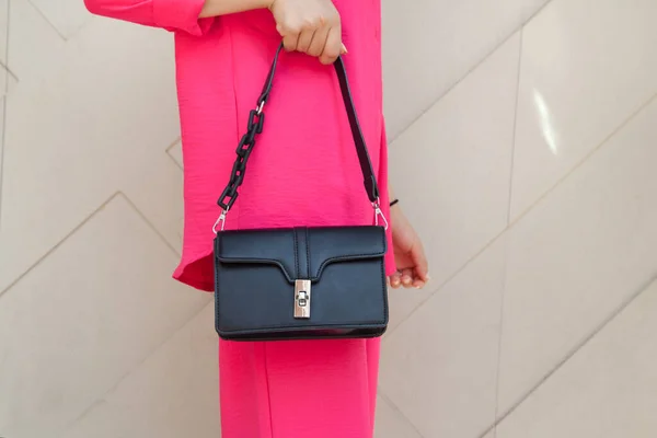 Lüks bir çanta taşıyan ve modaya uygun kıyafetler giyen genç bir kadın. Moda konsepti.