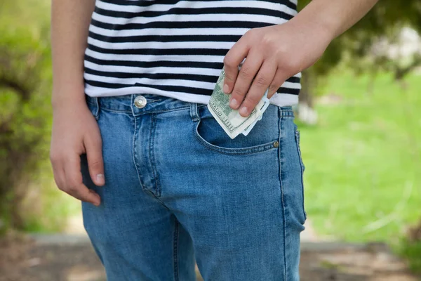 A man putting money in the pocket of jeans.