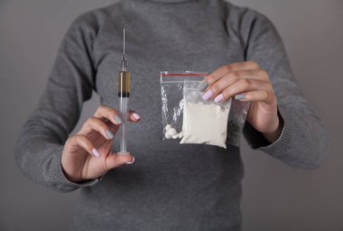 Elinde şırınga ve uyuşturucu tutan genç bir kadın. Suç ve uyuşturucu bağımlılığı kavramı..