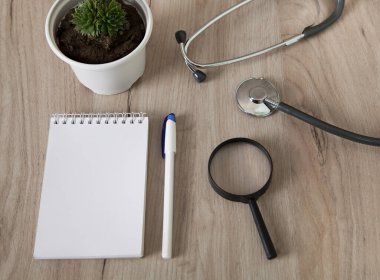 Stetoskop, defter, kalem ve büyüteç manzaralı ahşap zemin. Tıbbi konsept.