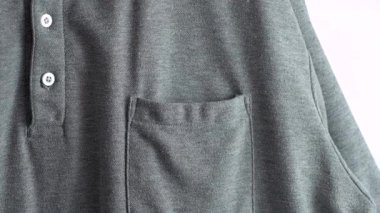 El, misafirin cebine sarı beyaz bir etiket takıyor. Düğmeli yakalı sıradan gri bir gömlek..