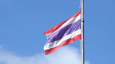 Tayland ulusal bayrağı, yarıya indirildi, mavi gökyüzüne karşı rüzgarda dalgalanıyor, taziyelerini ya da taziyelerini bildiriyor..