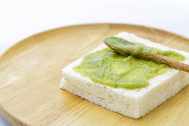 Pandan Muhallebi ile yakın plan beyaz ekmek, yuvarlak ahşap bir tabak üzerine yerleştirilmiş küçük ahşap spatula ekmek üzerinde dinleniyor.