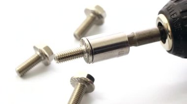 Beyaz arka planda üç benzer fındıkla çevrili bir bloğu döndüren elektrikli matkabın yakın çekimi, kullanım kolaylığını gösteriyor.