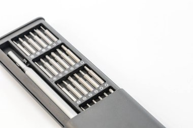 Çeşitli gümüş parçaları olan gri bir tornavida siyah bir çantada düzgünce düzenlenir. Alet temiz beyaz bir yüzey üzerinde fotoğraflanır, araçların karşıtlığını artırır.  