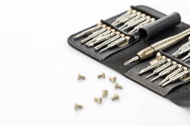 Beyaz bir yüzey üzerinde siyah deri bir çantada birkaç vida etrafa saçılmış hassas tornavidalar. Araçlar iyi korunmuş gibi görünüyor, profesyonel kullanıma işaret ediyor.