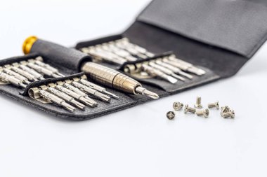 Beyaz yüzeyinde vidaları olan siyah deri bir çantada çeşitli parçaları olan hassas tornavidalar. Gümüş metal aletler ceplerinde duruyor ve kullanıma hazır..
