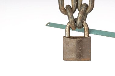 Görüntü, sağlam zincirlere asılmış asma kilit ve güvenlik ihlali ihtimalini vurgulayan demir testeresini gösteriyor..