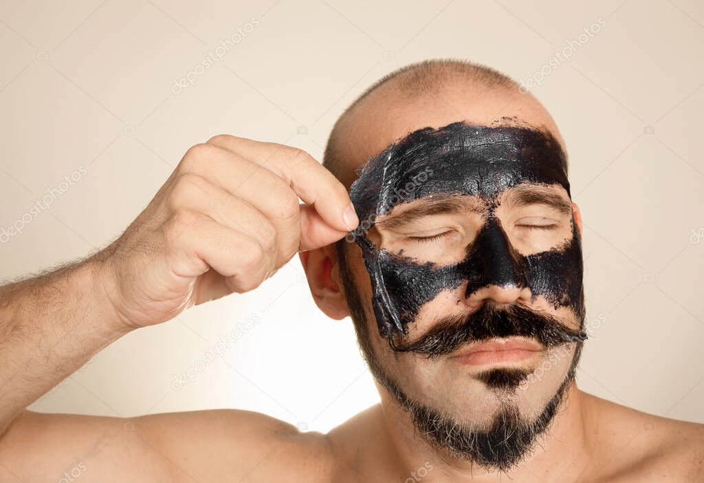 Adulto caucásico con barba y bigote elimina la máscara facial. Concepto