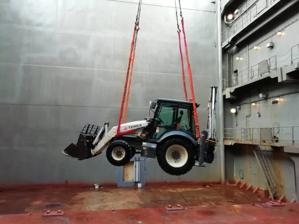 A alimentar o tractor no porão. Trabalho portuário. Dia de trabalho dos estivadores. Guindaste portal em ação. Trabalho duro e perigoso. Rússia. — Fotografia de Stock