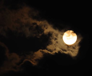 Dolunay yakın çekim ve ürkütücü beyaz bulutlar karanlık bir gece gökyüzüne karşı. Karanlık bir gecede büyük ay. Bulutlar çeşitli görüntülerde bir araya gelir. Gece gökyüzünde dramatik bulutlar olan dolunay..