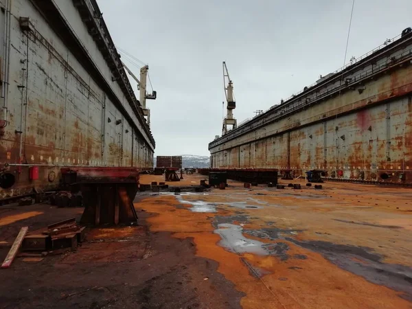 Old rusty floating dry dock. Dry docks are used for the construction, maintenance and repair of ships. Murmansk. Tall cranes are in the working dock. — Stock Photo, Image