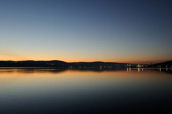 Vista nocturna de la bahía de Kola Murmansk es el puerto principal en el norte de Rusia. Hermosa puesta de sol con el reflejo de las luces en la bahía. Hermoso paisaje en el lado del cabo Abram. —  Fotos de Stock