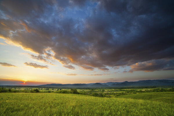 Драматический закат над зеленым полем