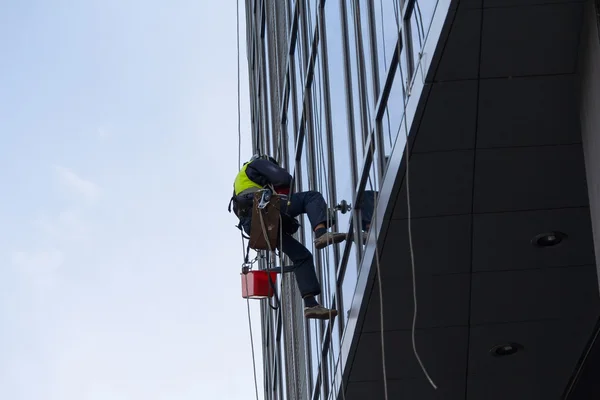 Escalador industrial lava la fachada de un edificio de varios pisos. Yo... — Foto de Stock