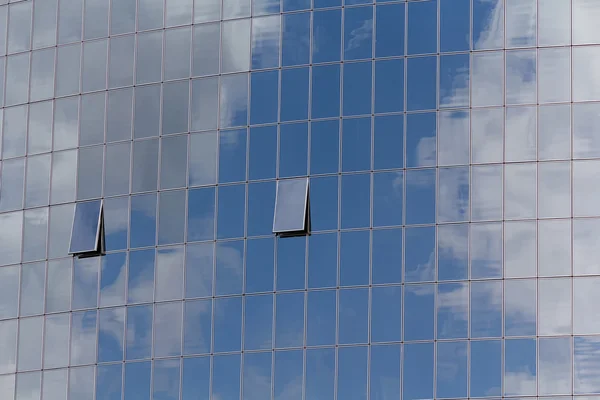Голубое небо и облака отражаются в окнах современного офисного здания — стоковое фото