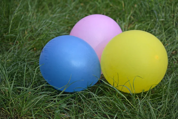 Multicolored balloons lying on green grass. Holidays — Stock Photo, Image