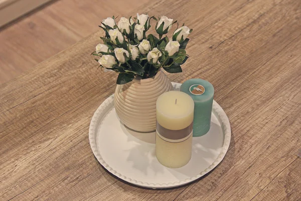 Velas e rosas em um vaso em uma mesa de madeira. Interior — Fotografia de Stock