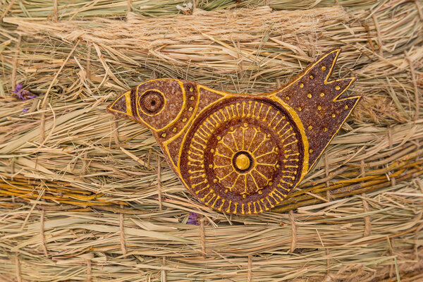 Stylized bird on a background of hay. Craft