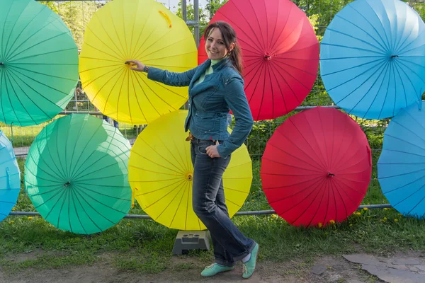 Mujer alegre en el fondo de paraguas multicolores — Foto de Stock