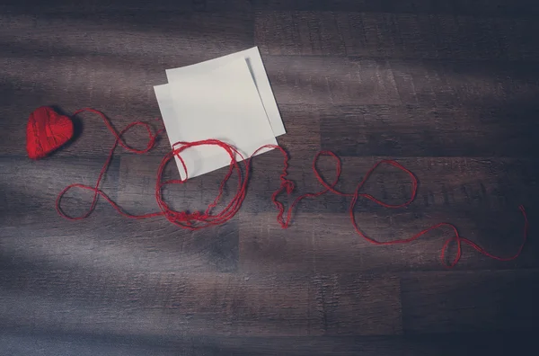 Czerwony clews w kształcie serca i tekst miłość na drewniane powrót — Zdjęcie stockowe