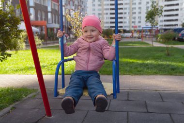 Evin yanındaki çocuk parkında salıncakta sallanan tatlı bir bebek. İnsanlar