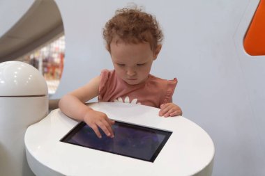 Çocuk bir oyun alanında eğitici bir uygulamayla meşgul oluyor. İnsanlar