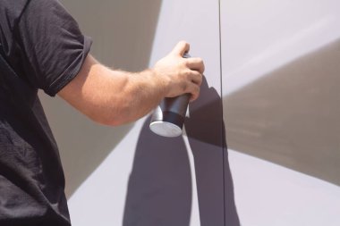 Grafiti yapan, sprey kutusunu elle tutan bir adam. Grafiti için sprey sprey boya. Sokak sanatçısı duvara grafiti yapıyor.