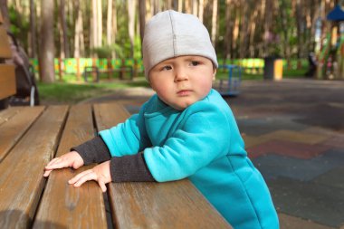 Çocuk serin havada parktaki oyun alanında oynar. İnsanlar