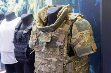 Askeri mağazada kamuflaj kıyafeti giymiş mankenler ve taktik teçhizatlar sergileniyor. Sanayi