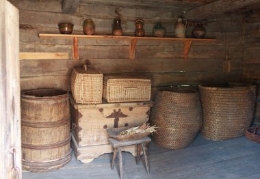 Chests, barrels and a shelf with dishes in the ancient peasant hut clipart