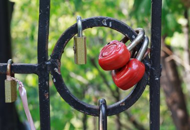 Red heart-shaped locks are hanging on the bridge lovers