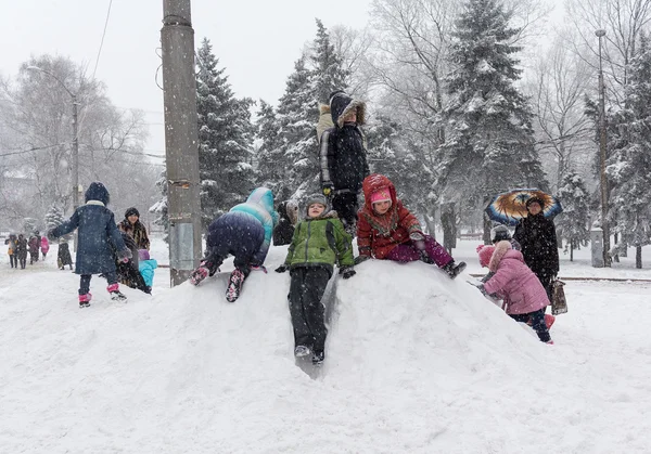 Макеевка, Украина - 07 января 2016 года: Дети играют на снежном холме на центральной площади — стоковое фото