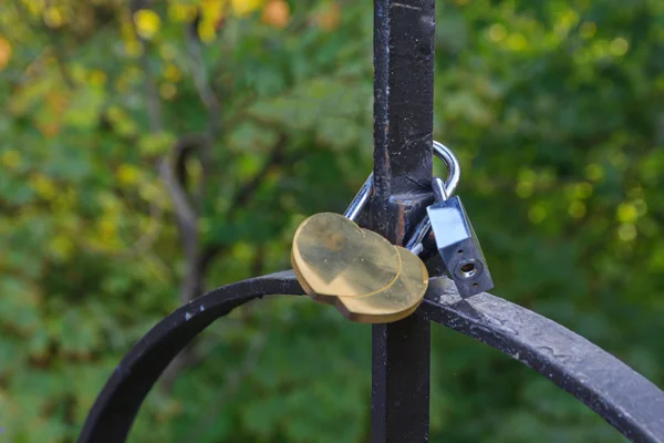 Padlock in the form of two gold hearts on the bridge of lovers — Stock Photo, Image
