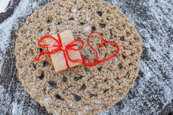 Gift and red hearts on a snowy background thread — Stock Photo, Image