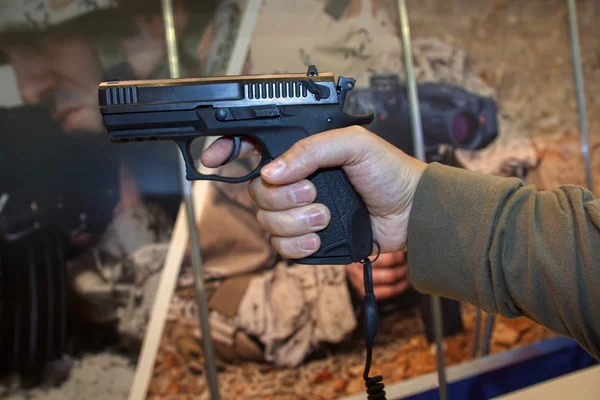 Πυροβόλο όπλο στο χέρι ενός άνδρα σε ένα φόντο πανό. Όπλο — Φωτογραφία Αρχείου