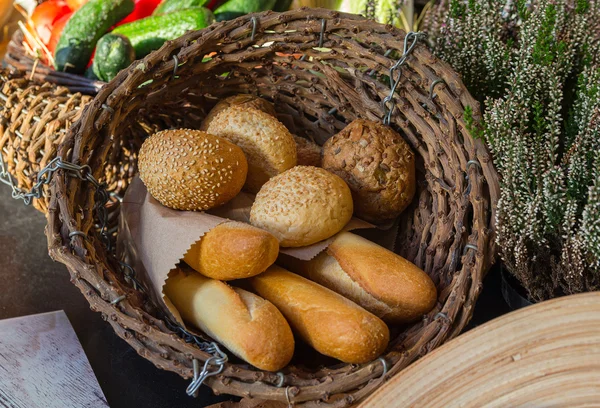 Brötchen und Baguettes auf einem Tisch in einem Weidenkorb. Lebensmittel — Stockfoto