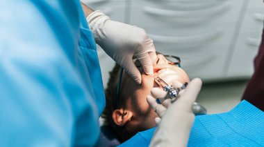 Genç hastaya anestezi yapmak için iğne kullanan tanınmamış bir diş hekiminin stok fotoğrafı..