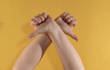 Sarı arka plandaki iki elin parmaklarının birleşimi. Başparmaklar aşağı.