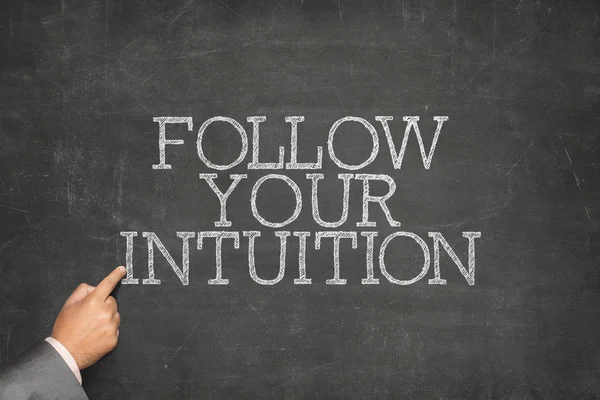 Follow Your Intuition text on blackboard with businessman hand pointing — Stock Photo, Image