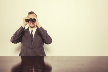 Dürbün ile ofis masa başında oturan işadamı