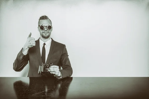 Geschäftsmann sitzt mit Fernglas am Schreibtisch — Stockfoto