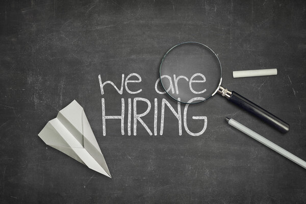 We are hiring concept on black blackboard with magnifying glass
